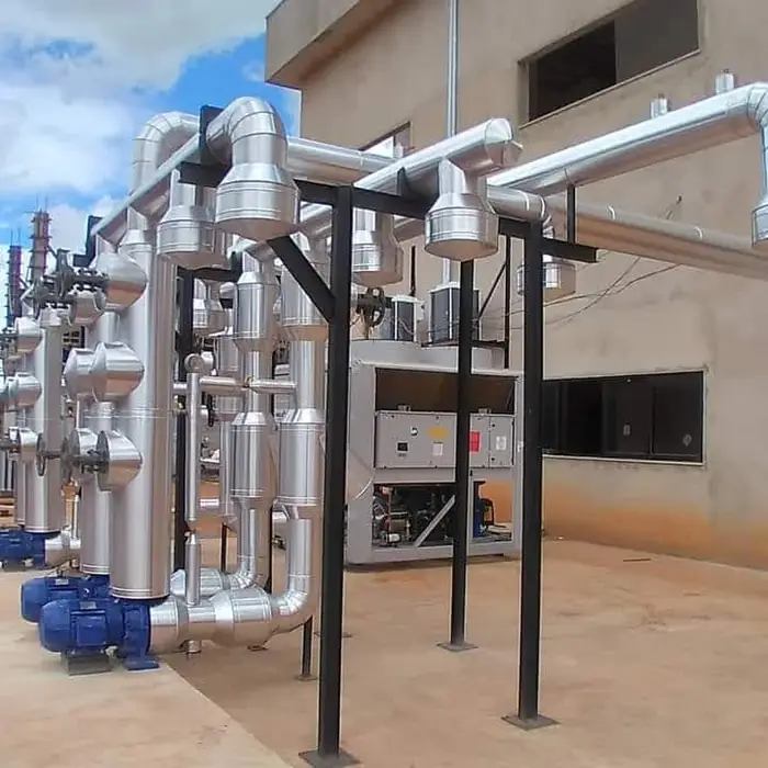 Tubulação frigorífica isolada em pipe rack junto à edificação industrial.