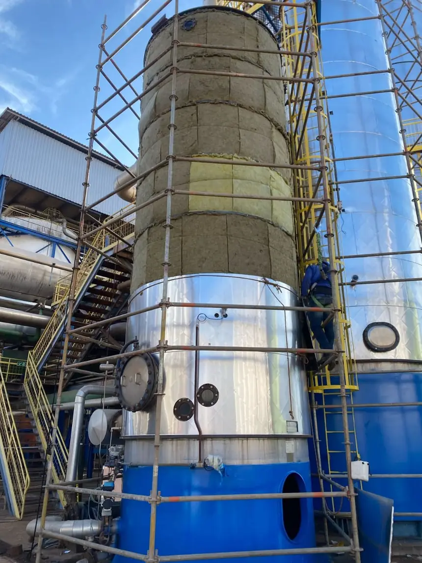 Aplicação de isolamento térmico e revestimento metálico em coluna vertical, com montagem de andaime.