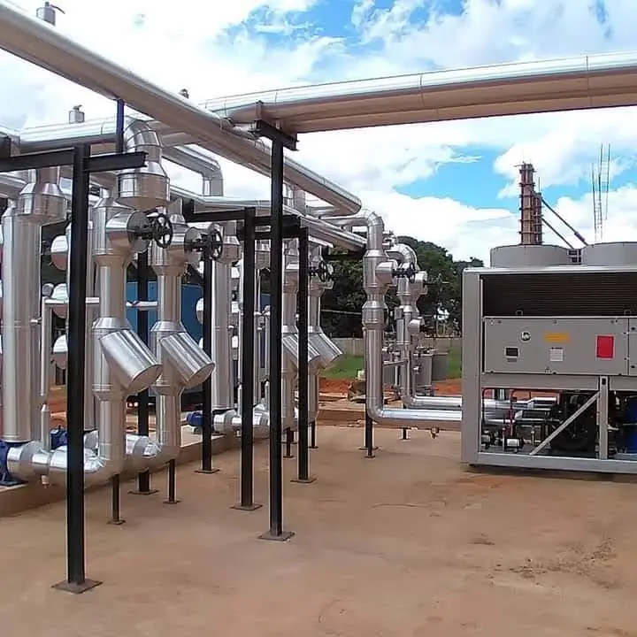 Rede de dutos isolados com revestimento em alumínio e chiller industrial ao lado.